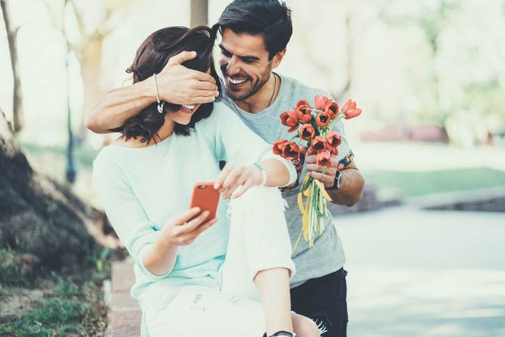 Young man surprising his girlfriend with bouquet of tulips Young man surprising his girlfriend with bouquet of tulips